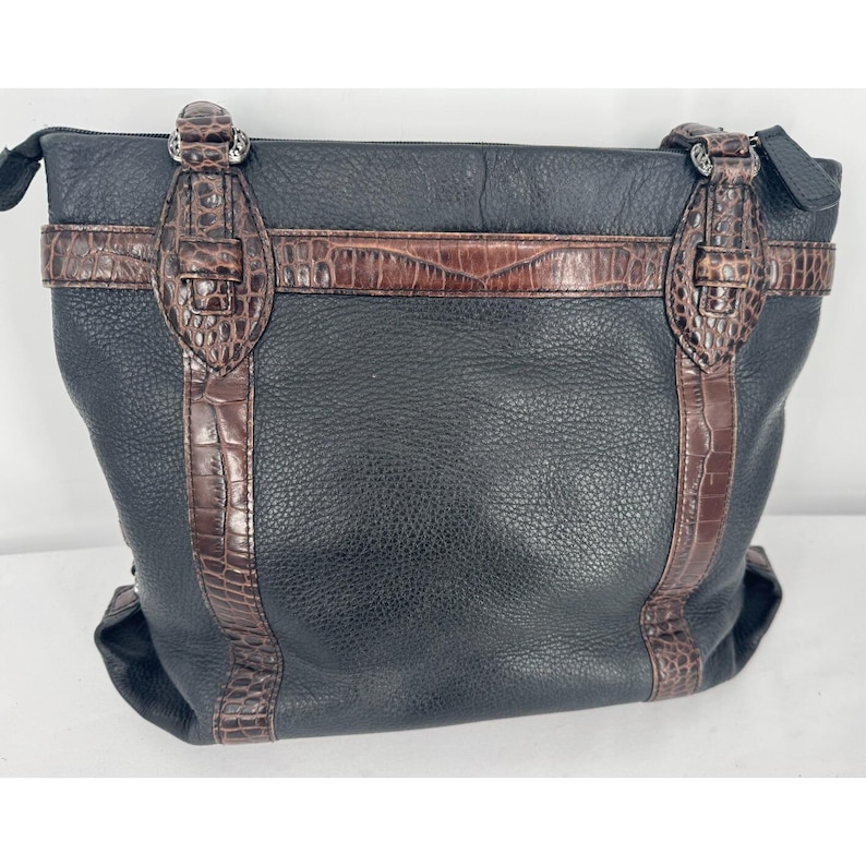 May include: Black leather tote bag with brown crocodile-textured accents. The bag features a zip closure and decorative buckles. The bag has a textured leather exterior and a structured shape.