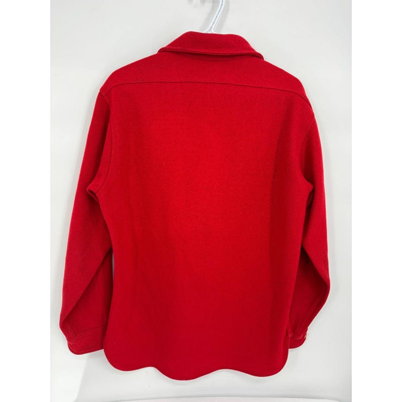 May include: A solid red long-sleeve shirt with a collared neckline. The shirt is made of a thick material and has buttoned cuffs. The shirt is hanging on a white hanger against a white background.