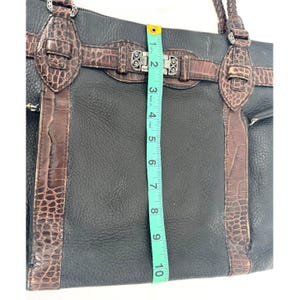 May include: Black leather tote bag with brown faux crocodile accents and silver-tone hardware. The bag measures approximately 10 inches in height. Features include a top zipper closure, braided handles, and multiple pockets.