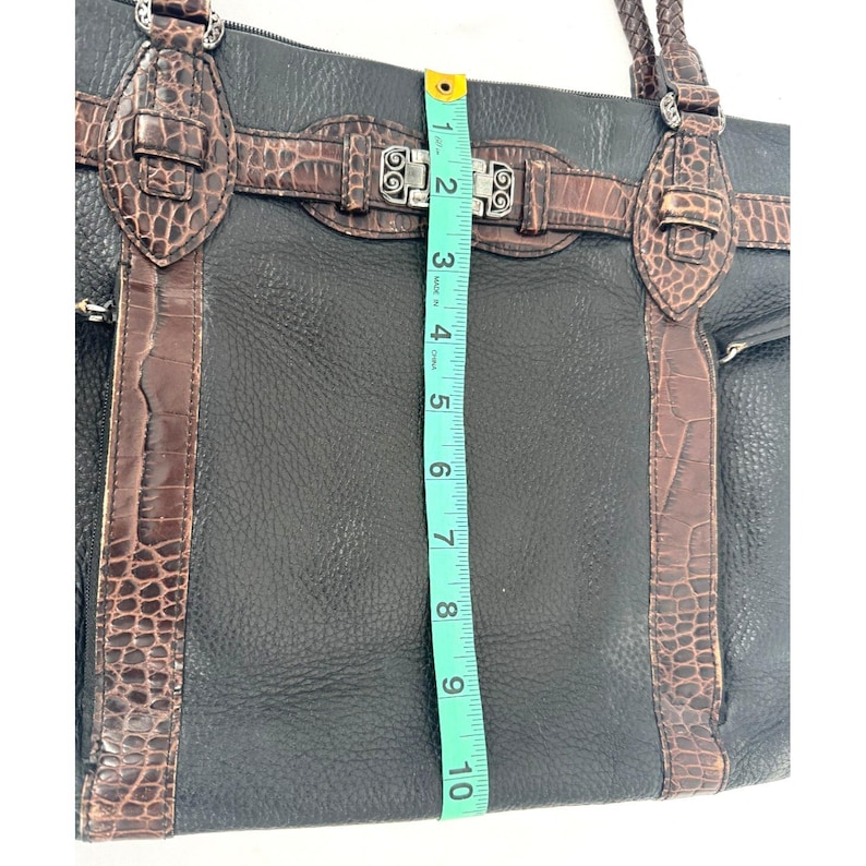 May include: Black leather tote bag with brown faux crocodile accents and silver-tone hardware. The bag measures approximately 10 inches in height. Features include a top zipper closure, braided handles, and multiple pockets.