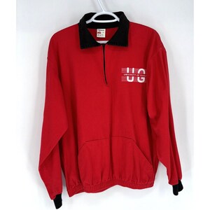 May include: Red long-sleeved sweatshirt with a black collar and black cuffs. The sweatshirt has a zip fastening and a kangaroo pocket. The front of the sweatshirt features a white graphic that says "University of Guelph" and "UG".