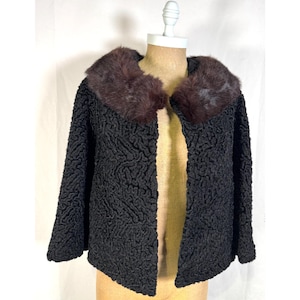 Peut inclure: Veste noire texturée avec un col en fourrure marron foncé, présentée sur un mannequin. La veste a une texture bouclée distinctive et un design classique. Le col en fourrure ajoute une touche de luxe au vêtement.