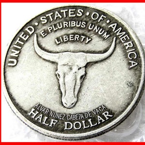 May include: A silver half dollar coin with the image of a steer's head and the text "United States of America, E Pluribus Unum, Liberty, Alvar Nunez Cabeza de Vaca, Half Dollar".