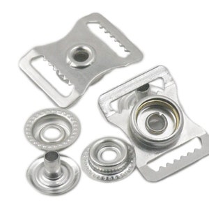 Puede incluir: Broches de presión de metal plateado con una hebilla. Los broches se utilizan para unir telas. La hebilla se utiliza para asegurar una correa o cinturón.