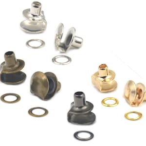 May include: Assortment of metal snap fasteners in silver, gold, and bronze. The fasteners are in various shapes and sizes, with some having a round shape and others having a more rectangular shape. The fasteners are used for attaching fabric or leather together.