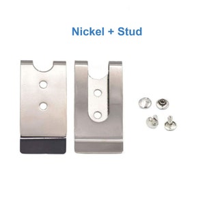 Puede incluir: Dos clips de cintur&oacute;n de metal niquelado con respaldo de goma negra. Los clips est&aacute;n dise&ntilde;ados para sujetarse a un cintur&oacute;n o cintura. La imagen tambi&eacute;n muestra cuatro remaches de metal plateados.