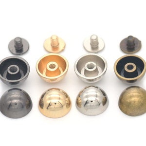 Op de afbeelding: Een verzameling van vier sets metalen koepelnagels in zwart, goud, zilver en antiek messing. Elke set bevat een koepelvormige dop en een pen. Ideaal voor leerbewerking en doe-het-zelf projecten.