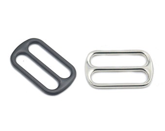 May include: Two metal slider buckles, one black and one silver. Both are rectangular with two oval openings.
