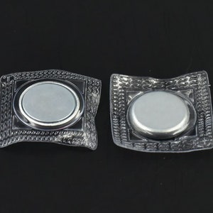 May include: Two clear plastic packages each containing a round silver magnetic button. The buttons are designed for sewing onto fabric.