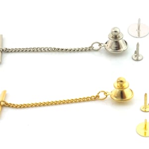 May include: Two collar stays, one silver and one gold, with chains and a pin. The silver collar stay has a round top with a small ball on top. The gold collar stay has a round top with a small ball on top. Both collar stays have a chain attached to the top and a pin attached to the bottom.