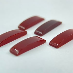May include: Five red carnelian cabochons, each shaped like a slightly curved rectangle.