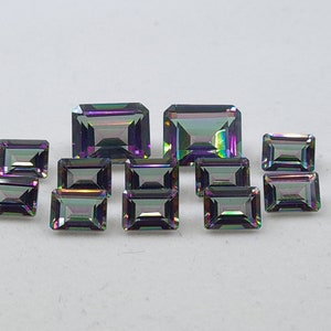 May include: Assortment of iridescent gemstones in various sizes and shapes, cut in an emerald shape. The gemstones are a mix of purple, blue, and green.