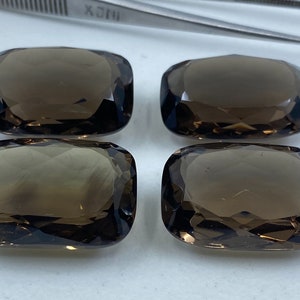 Peut inclure: Quatre pierres précieuses rectangulaires facettées de couleur brune. Les pierres précieuses sont disposées en deux rangées de deux.