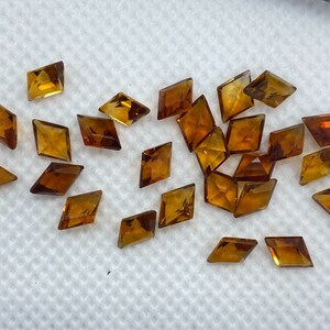 Puede incluir: Una colecci&oacute;n de veintid&oacute;s peque&ntilde;as piedras preciosas talladas en forma de diamante de color &aacute;mbar.