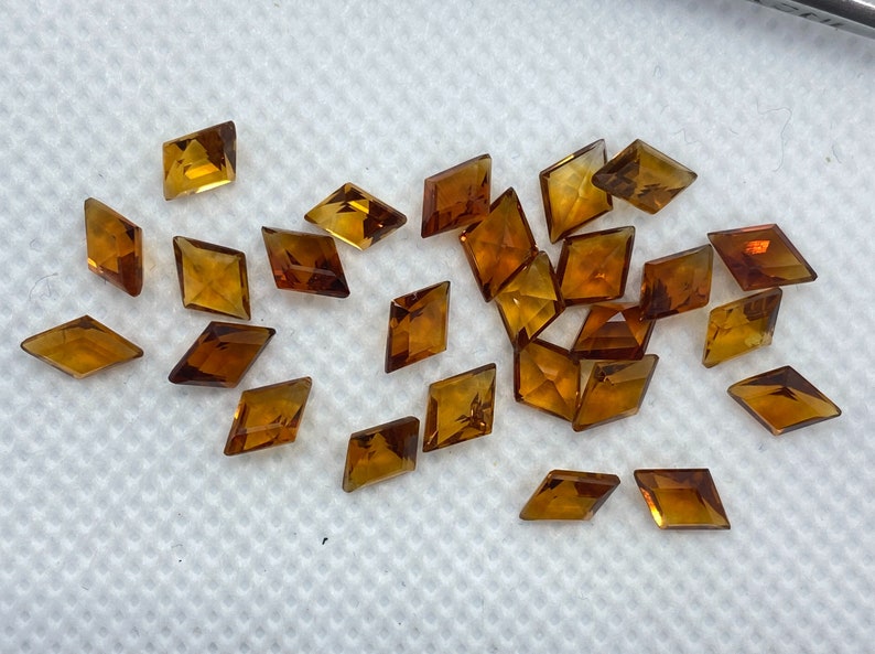 Puede incluir: Una colecci&oacute;n de veintid&oacute;s peque&ntilde;as piedras preciosas talladas en forma de diamante de color &aacute;mbar.
