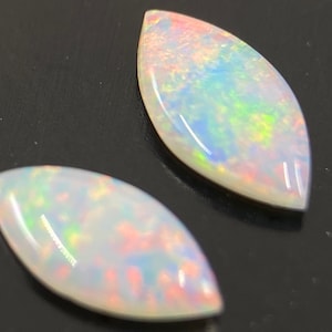 May include: Two white opal marquise-shaped gemstones with iridescent rainbow colors.