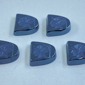 Puede incluir: Cinco cabujones de piedra preciosa semicirculares de color azul oscuro con un diseño tallado. Cada cabujón tiene un diseño tallado diferente.