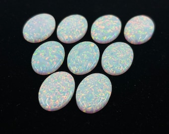 May include: A collection of ten oval-shaped white opals with iridescent rainbow flashes. The opals are arranged in a triangular pattern on a black background.