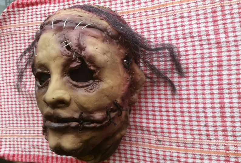 May include: A realistic horror mask with stitched-up wounds and a sewn-shut mouth. The mask is made of latex and has a realistic skin tone. It is designed to be worn for Halloween or other fancy dress events.