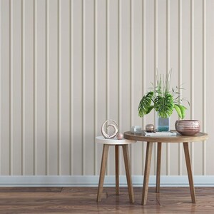 a minimalist interior design with a wooden table and two small side tables against a wall with vertical stripes. The table has a vase with plants and decorative items on it, creating a cozy and inviting atmosphere.