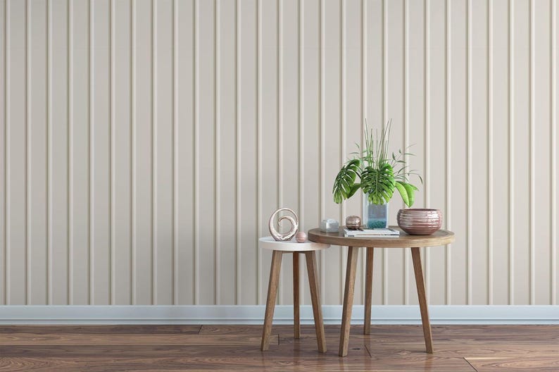 a minimalist interior design with a wooden table and two small side tables against a wall with vertical stripes. The table has a vase with plants and decorative items on it, creating a cozy and inviting atmosphere.