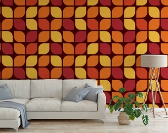 May include: A white sectional sofa with a throw blanket and a plant in a pot sits in front of a wall with a retro geometric pattern in shades of red, orange, and yellow.