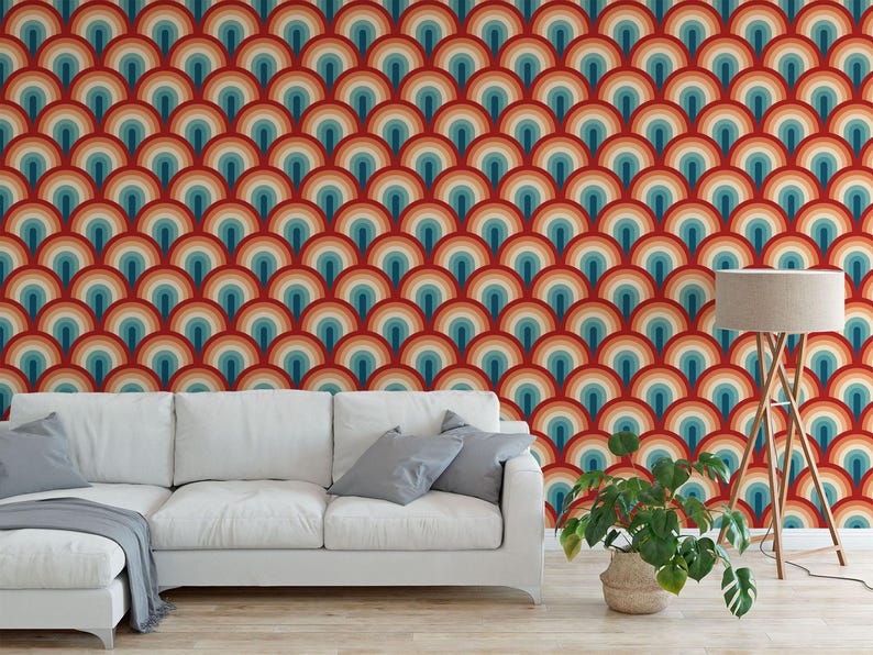 a living room with a white sofa and a potted plant. The sofa is positioned against a wall with a vibrant, repeating pattern of colorful circles in shades of red, orange, yellow, green, blue, and purple. The potted plant is placed on the floor next to the sofa, adding a touch of greenery to the space.