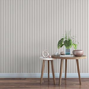 a minimalist interior design with a wooden table and two small side tables against a gray wall. The table has a plant and a bowl on it, creating a cozy and inviting atmosphere.