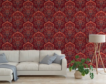 Puede incluir: Un sofá blanco con una manta de tiro gris se encuentra frente a una pared roja con un patrón repetitivo de intrincados diseños florales. Una lámpara de pie con una pantalla beige y una planta verde en maceta también están en la habitación.