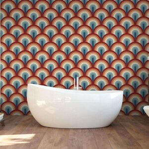 a modern bathroom with a large, white freestanding bathtub in the center. The walls behind the bathtub are covered in a vibrant, repeating pattern of circles in various colors, creating a visually striking and unique design. The bathroom also includes a toilet, a towel rack, and a potted plant, contributing to the overall aesthetic and functionality of the space.