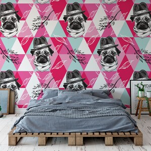 Puede incluir: Un dormitorio con un papel tapiz de patr&oacute;n geom&eacute;trico rosa, azul y blanco con un dise&ntilde;o repetido de un pug con sombrero. El papel tapiz est&aacute; detr&aacute;s de una cama con un edred&oacute;n gris y un marco de madera.