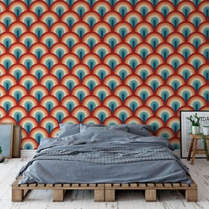 a bedroom with a bed, a wooden table, and a colorful, patterned wallpaper behind the bed.