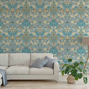 May include: A teal blue wallpaper with a repeating floral pattern in shades of yellow, white, and brown. The wallpaper is displayed in a living room setting with a sofa, a floor lamp, and a potted plant.