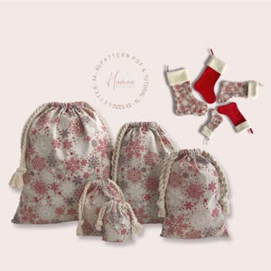 May include: A selection of drawstring gift bags and Christmas stockings. The bags are beige with a red and white snowflake pattern, and the stockings are red with white trim and a snowflake design. The bags vary in size and have rope drawstrings.