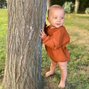 Baby model with neck band sweatshirt romper.