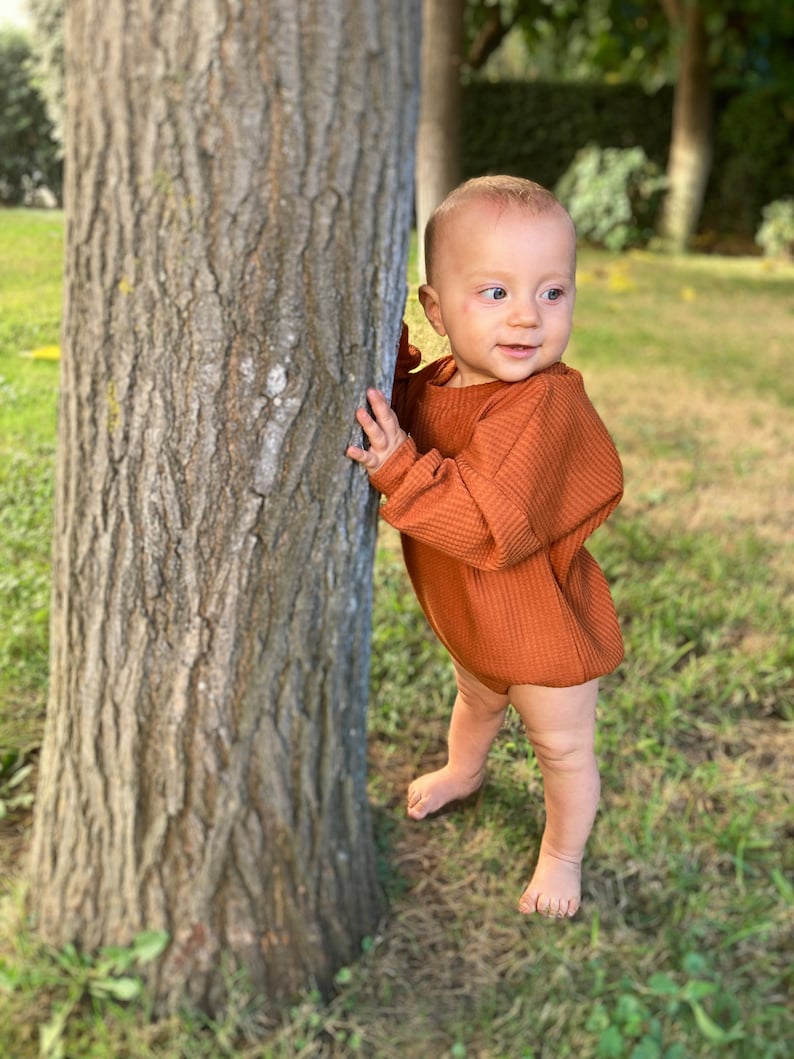 Baby model with neck band sweatshirt romper.