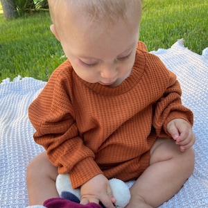 Baby model with neck band sweatshirt romper.