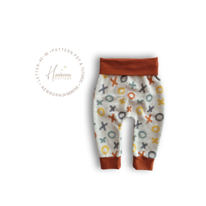 Op de afbeelding: Babybroek van lichtgrijze gem&ecirc;leerde stof met een herhalend patroon van handgetekende X- en O-symbolen in mosterdgeel, roestoranje en leiblauw. De broek heeft een effen roestoranje tailleband en boorden bij de enkels.