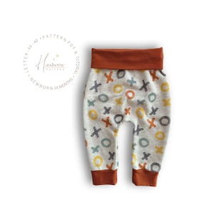 May include: Grey baby trousers with a pattern of orange, yellow and blue circles and Xs. The trousers have a rust-coloured waistband and cuffs.