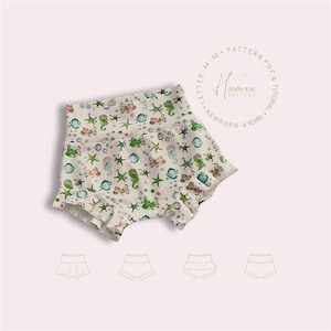 May include: A white fabric baby bloomer with a seahorse, fish, and starfish pattern. The bloomer has a ruffled hem and is shown with a pattern layout guide.