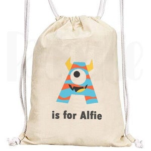 May include: A white drawstring bag with a blue, orange and yellow monster graphic that says "A is for Alfie".