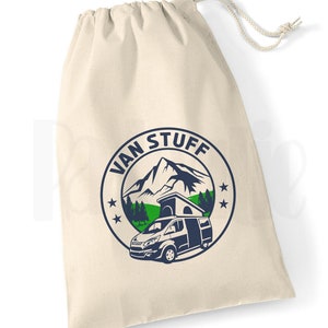 May include: A white canvas drawstring bag with a blue and green logo that says "VAN STUFF" and features a mountain, trees, and a camper van.