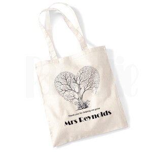 May include: A white canvas tote bag featuring a black and white tree design in the shape of a heart. The text "Thank you for helping me grow" and "Mrs Reynolds" is printed below the tree.