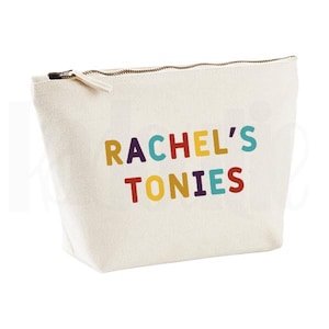 May include: Cream canvas cosmetic bag with a zip closure. The bag has the text "RACHEL'S TONIES" in colourful block letters. The zip is gold-coloured.