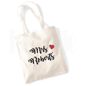 May include: A white canvas tote bag with black text that reads "Mrs. Roberts" and a red heart.