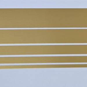 May include: Four horizontal strips of gold-coloured tape with a white border.
