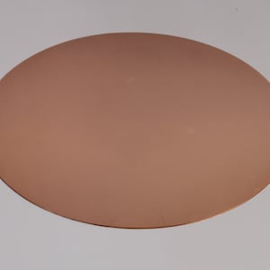 May include: A copper-coloured, oval-shaped metal plate. The plate has a smooth, reflective surface and a uniform colour. The shape is a flattened oval, suitable for various uses.