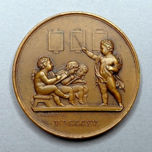 Op de afbeelding: Een bronzen ronde medaille met een reliëfsculptuur die cherubijnachtige figuren in een klaslokaal afbeeldt. Eén cherubijn wijst naar een bord terwijl anderen studeren. De inscriptie "BONARD F." en "MDCCCXXV" zijn zichtbaar.