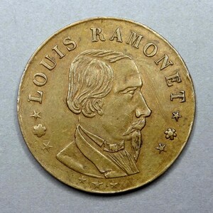 May include: A gold-colored coin with the inscription "LOUIS RAMONET" and a profile portrait of a man with a beard.