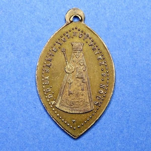 Peut inclure: Un pendentif en métal doré avec une image religieuse d'une femme portant une couronne et une robe. Le texte autour de l'image est "N.D. LA. SARTE. EZ. PRIEZ. P. NOUS".